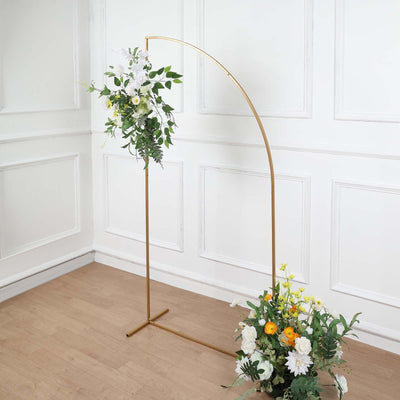 Gold floral arch with white and yellow flowers on a wooden floor.