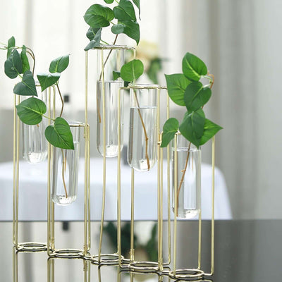 Stylish gold plant holder with glass vases and greenery