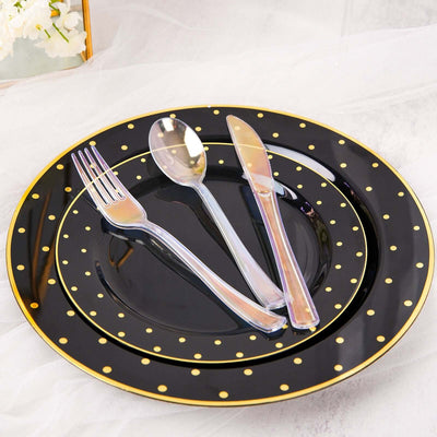Black polka dot dinnerware set with fork, knife, and spoon on a table.