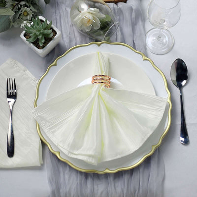 Elegant table setting with a pale green napkin and gold ring on a decorative plate.