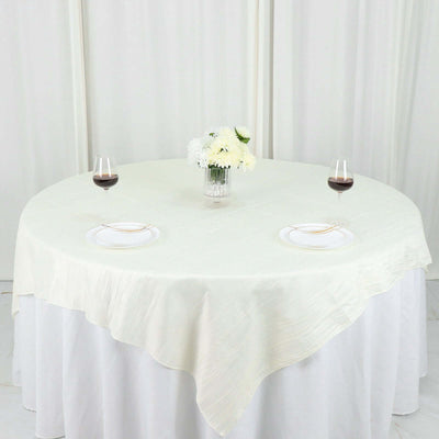 Round table set with white tablecloth, plates, and wine glasses.