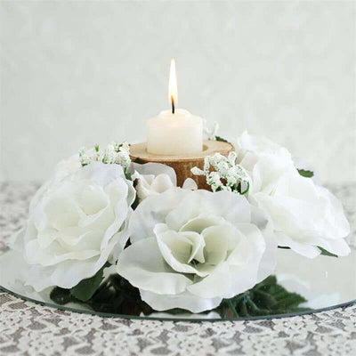 Floral centerpiece with white roses and a candle on a mirrored base.