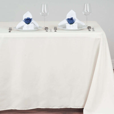 Elegant dining table set with white tablecloth, plates, and decorative napkins.
