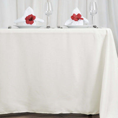 Elegant dining table setting with red flowers and glassware.