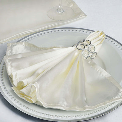 Silk napkin elegantly folded with a jeweled napkin ring on a decorative plate.