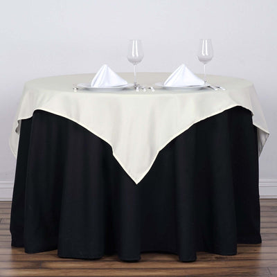 Elegant round table set with white dinnerware and napkins on a black skirt.