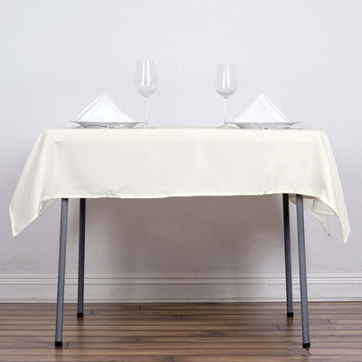 Elegant cream tablecloth draped over a table with glassware and napkins.