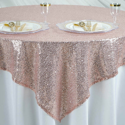 Rose gold sequin tablecloth draped over a round table set for dining.