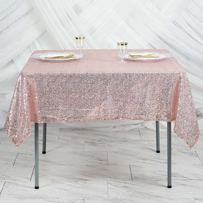 Rose gold sequin tablecloth draped over a table with plates and glasses.