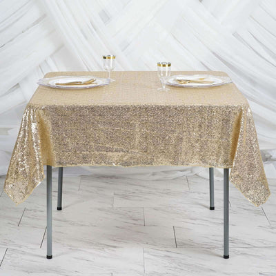 Gold sequin tablecloth draped over a table with elegant glassware and plates.