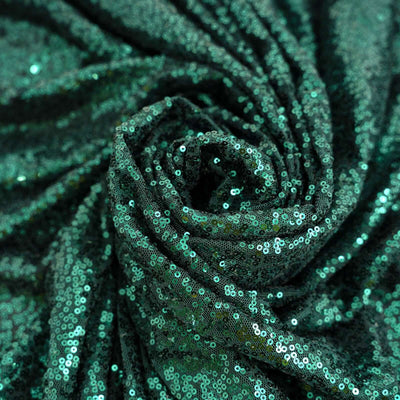 Green sequin fabric draped in a spiral, showcasing shine and texture.