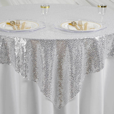 Silver sequin tablecloth draping elegantly over a round table setting.
