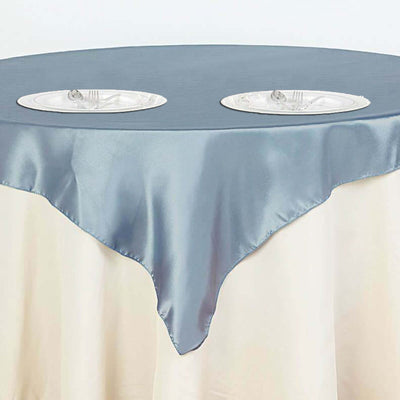 Elegant round table with a light blue satin tablecloth and two plates.