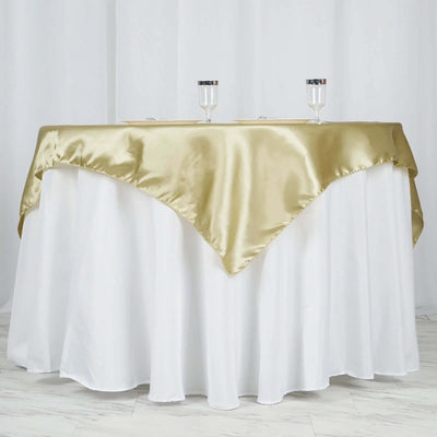 Gold satin tablecloth draped over a white table with glasses on top.