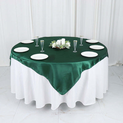 Round table set with a green satin tablecloth and white plates.