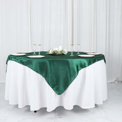 Green satin tablecloth on a round table set for dining.