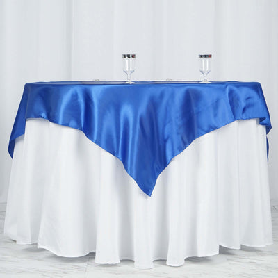Blue satin tablecloth draped over a white table with glasses on top.