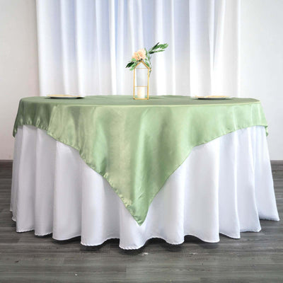 Green satin tablecloth draped over a white table with a floral centerpiece.