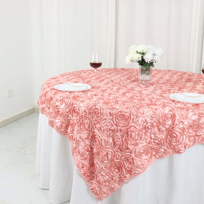 Pink rose-patterned tablecloth draped over a round table with wine and flowers.
