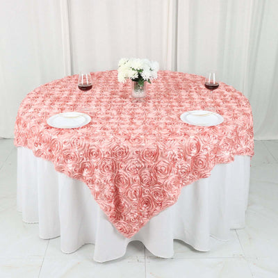 Pink rose-patterned tablecloth on a round table with floral centerpiece and wine glasses.