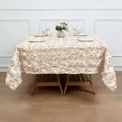 Rose-patterned tablecloth on a wooden table with glasses and flowers.