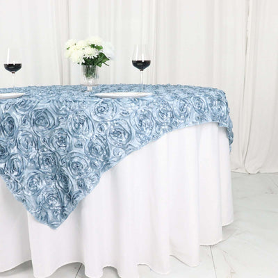 Blue rose-patterned tablecloth draped over a white table with wine glasses.