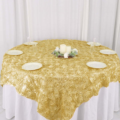 Gold rose-patterned tablecloth on a round table with plates and candles.