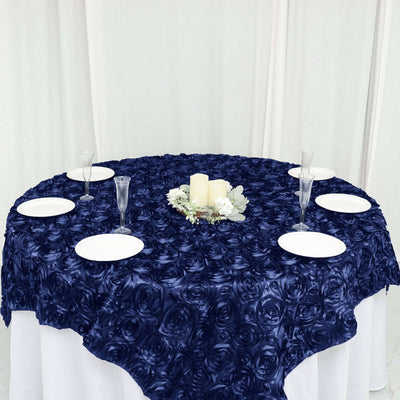 Navy rose-patterned tablecloth on a round table with plates and candles.