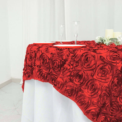 Red rose tablecloth draped elegantly over a white table with glassware and candles.