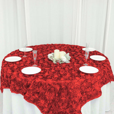 Red rose tablecloth draped over a round table set for a dining occasion.
