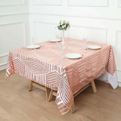 Rose gold geometric tablecloth on a wooden table with glassware and plates.