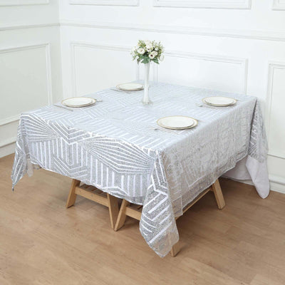 Elegant white tablecloth with geometric patterns draped over a wooden table.