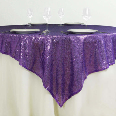 Purple sequin tablecloth draped over a round table set for dining.