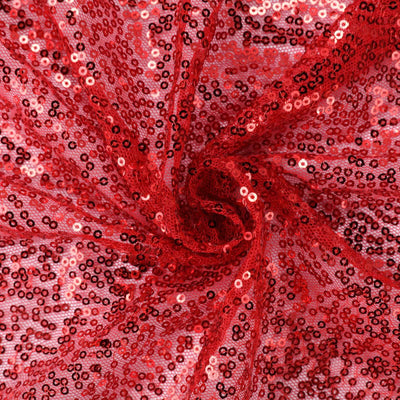 Red sequin fabric with sparkling texture in a swirling pattern.