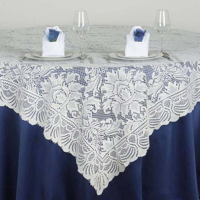 White lace tablecloth elegantly draped on a blue table with glassware and napkins.