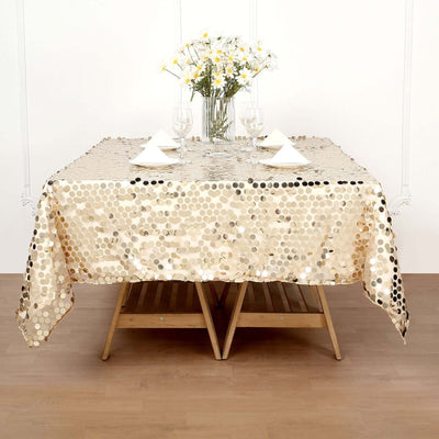 Gold sequin tablecloth draped over a wooden table set for dining.