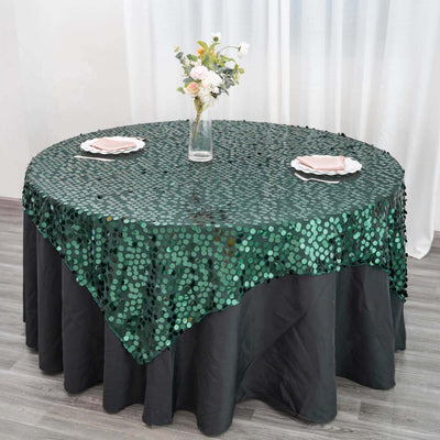 Green sequin tablecloth draped on a round table with floral centerpiece.