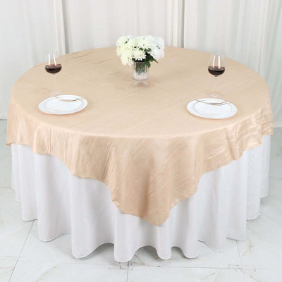 Elegant round table with beige tablecloth, wine glasses, and floral centerpiece.