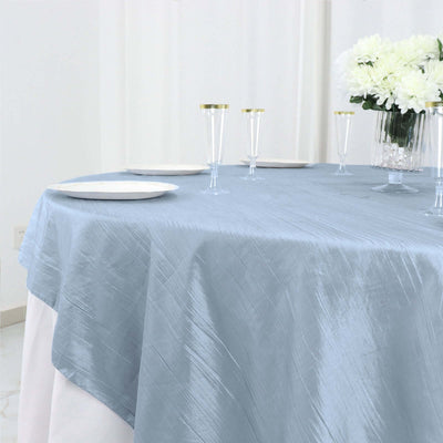 Light blue tablecloth draped elegantly over a round table with clear glassware.