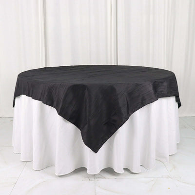 Black tablecloth draped over a round table with a white skirt.