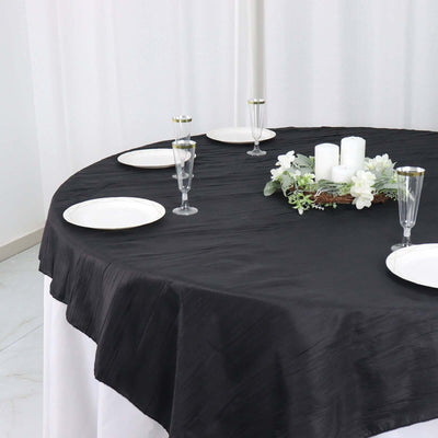 Elegant black tablecloth draped over a round table set for dining.