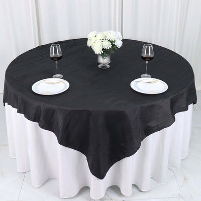 Elegant round black tablecloth on a white table with wine glasses and plates.