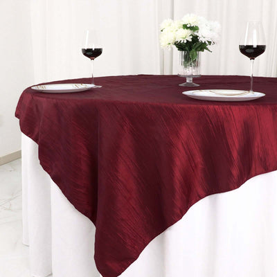 Burgundy tablecloth on a dining table with wine glasses and flowers