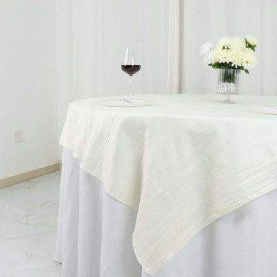Elegant cream tablecloth draped over a table with wine and flowers.