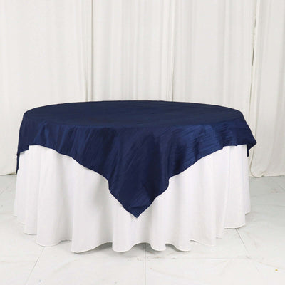 Navy blue tablecloth draped over a round table with a white table skirt.