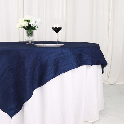 Navy blue tablecloth draping over a white table with flowers and wine glass.