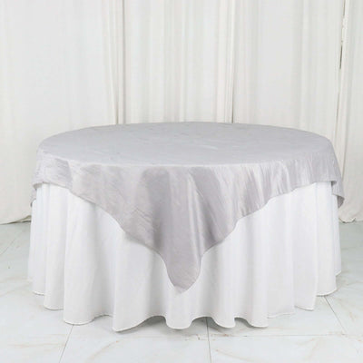 Round table with elegant gray tablecloth draped over white table skirt.