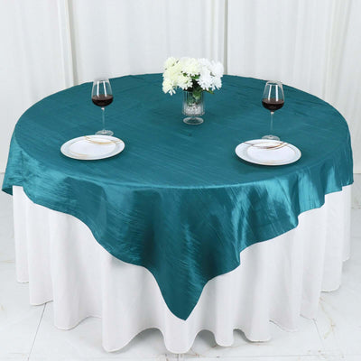 Teal round tablecloth on a white table with wine glasses and flowers
