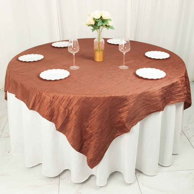 Brown textured tablecloth draped over a round table with plates and glasses.