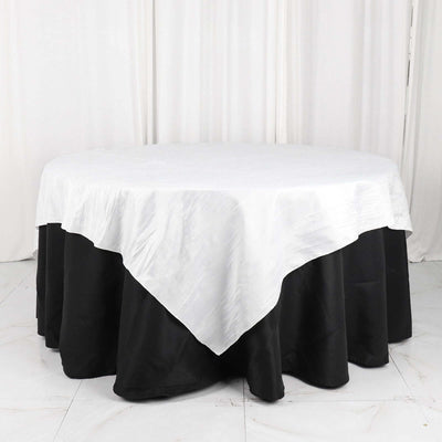 Round table with a white tablecloth and black skirt